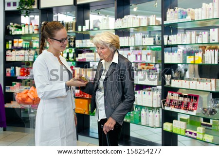 Attractive female pharmacist helping a senior lady choose her toiletries offering her advice with a smile
