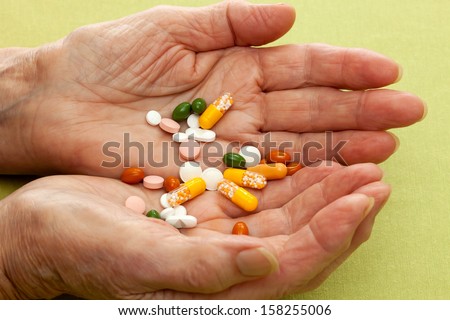 Cupped hands of an old lady with a cocktail of tablets, capsules and pills given to her as medication and treatment for ailments and as supplements to her diet
