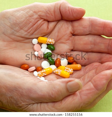 Senior woman holding assorted tablets and capsules in her cupped hands conceptual of health care for the elderly