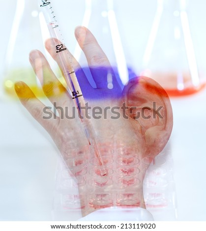 Concept image showing the danger of genetic modification resulting in grotesque abnormalities with a human hand growing an ear in place of a thumb on a background of genetic typing and lab glassware