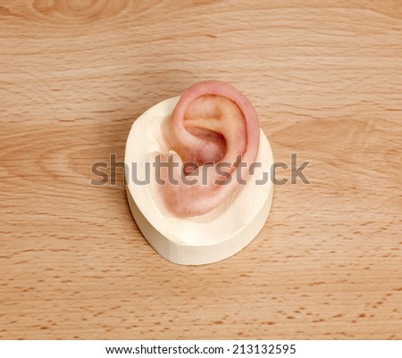 Silicone Human Ear with Magnetic Locks on Wooden Table. Used for Patients with Ear Defects or film props.