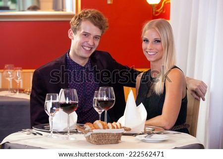 Happy smiling couple enjoying a night out dining in an upmarket restaurant with red decor