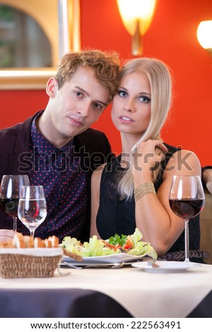 Romantic Young Lovers in Their Dinner Date at Restaurant, Seriously Looking at Camera.