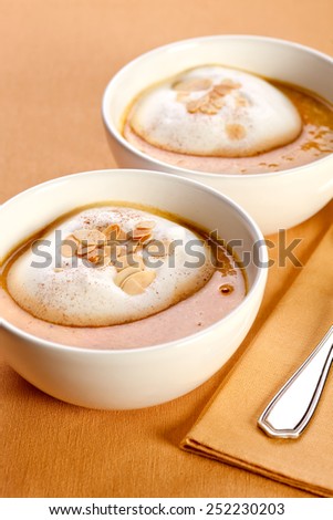 Carrot soup with milk foam and sliced almonds.