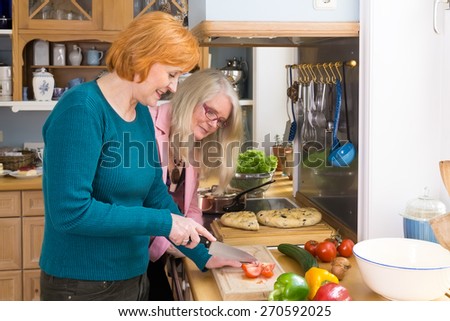 Smiling Middle Age Mom to her Serious Friends How to Prepare her Favorite Recipe While Having a Bonding Moments at the Kitchen.