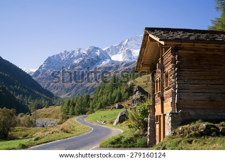 Quaint Wood Cabin Beside Paved Single Lane Mountain Road Through Snow Capped Alps, Valais, Switzerland.