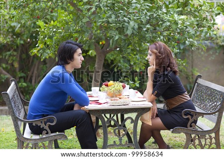 Two young people face off across a table at a restaurant during a disagreement in a sign of conflict