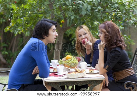 Three young college friends having a serious discussion over a cup of coffee seated at a table at an outdoor cafe