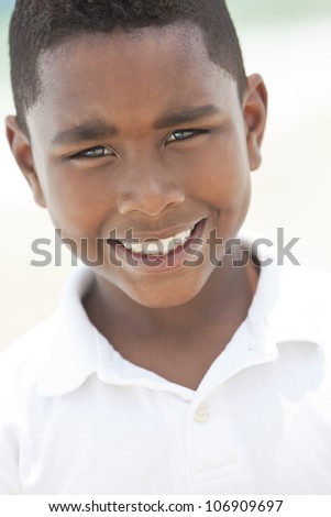 A happy smiling young African American boy at the beach in the summer