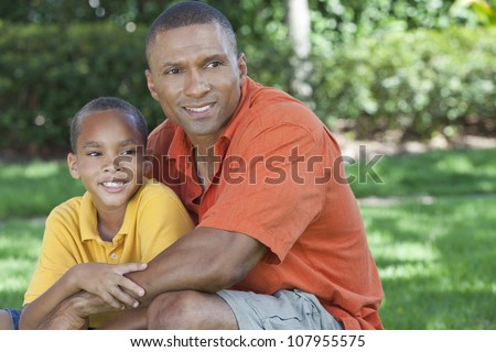 A happy African American man and boy, father and son, family together outside in summer sunshine