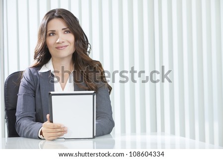 Young woman executive or businesswoman in sitting at a desk in an office using a tablet computer