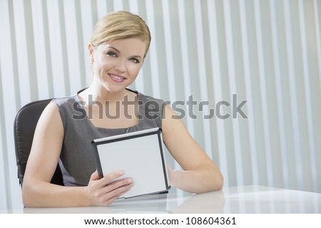Young woman executive or businesswoman in sitting at a desk in an office using a tablet computer