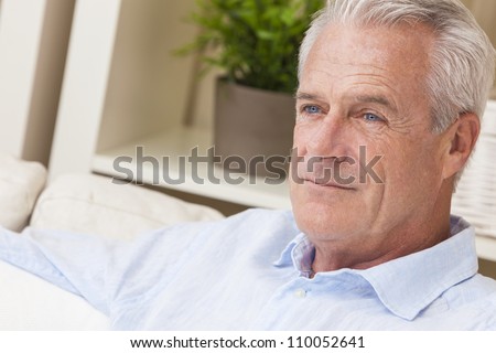 Happy and healthy senior man sitting on a sofa at home thoughtful and happy