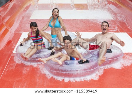 A happy family of mother father and children son and daughter having fun on vacation on a slide at a water park A happy family of mother father and children son and daughter having fun on vacation on a slide at a water park