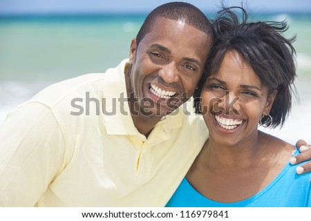 A happy smiling laughing African American man and woman couple at the beach in the summer
