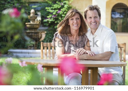 Attractive, romantic and happy middle aged man and woman couple in their forties, sitting together outside in a garden with flowers