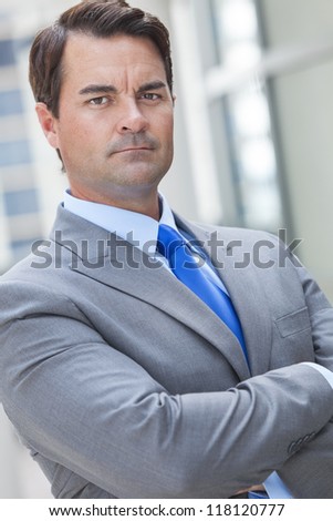 Successful smart businessman or man serious and thinking with arms folded in a suit in a modern city