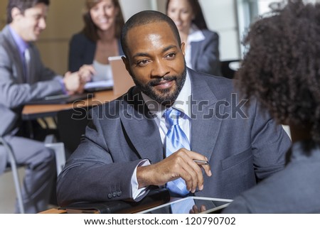 An African American businessman in a meeting with businesswoman colleague