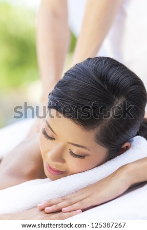 An Asian Chinese woman relaxing outside at a health spa while having a massage treatment