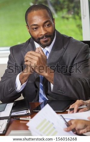 An African American businessman or man in an office meeting with team of colleagues