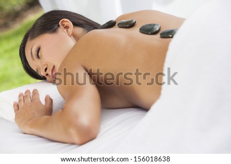 An Asian Chinese woman relaxing outside at a health spa while having a hot stone treatment or massage