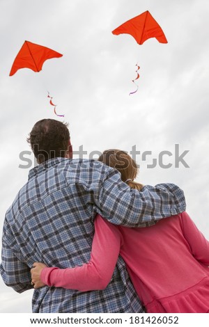 Relationship troubles concept photograph of man & woman couple flying a red kite each in different directions