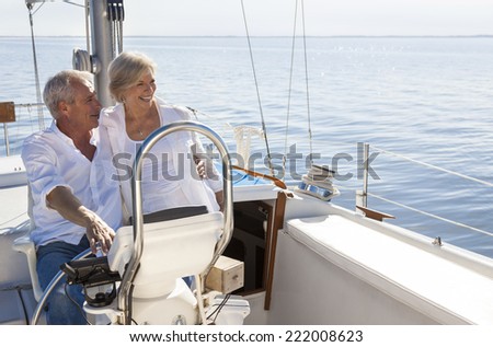 A happy senior couple sailing and sitting at the wheel of a sail boat on a calm blue sea