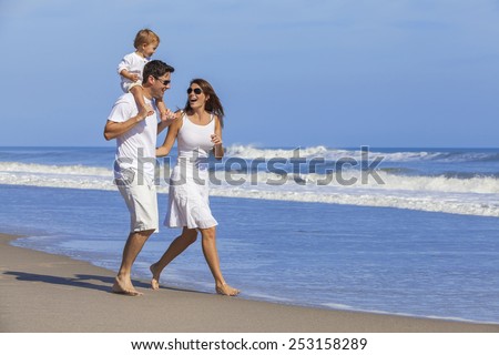 Happy Man and woman boy child couple family in white clothes walking playing on a deserted empty tropical beach with bright clear blue sky