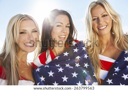 Three beautiful young women wearing bikinis, wrapped in American flags, smiling, laughing and having fun party on a sunny beach