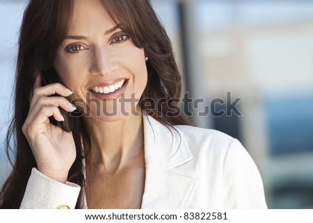 Outdoor portrait of a beautiful happy brunette woman or businesswoman in her thirties talking on her cell phone