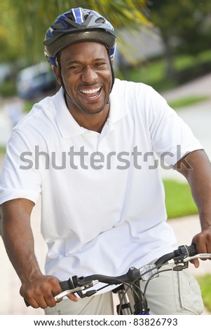 A handsome happy African American man with a big smile riding his bicycle outside