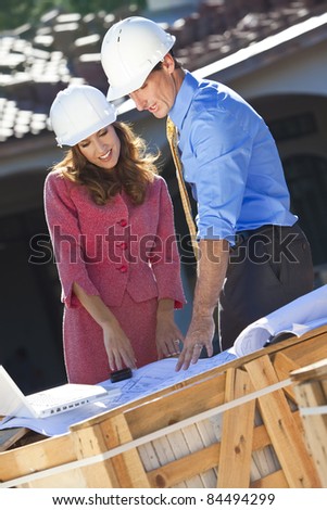 Man and woman in hard hat meeting on construction site with architect plans and a laptop computer.