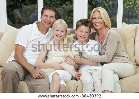 An attractive happy family of mother, father, son and daughter sitting on a sofa at home having fun with pet dog