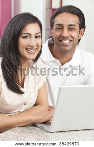 Asian Indian couple, husband & wife, man and woman, using laptop computer in the kitchen at home