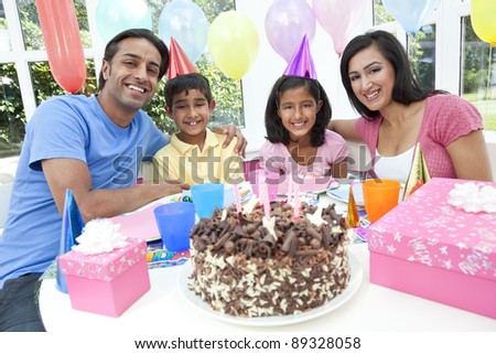 Asian Indian family, mother, father, son & daughter celebrating a birthday party with a chocolate cake