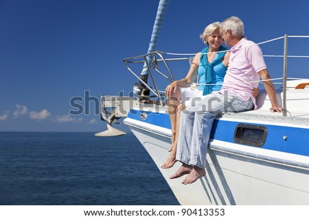 A happy senior couple sitting on the deck of a sail boat on a calm blue sea