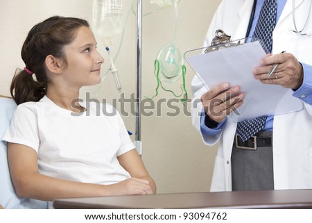 Young girl in a hospital bed being given advice by a male doctor with stethoscope and clip board