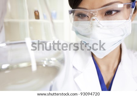 A Chinese Asian female medical or scientific researcher or doctor using looking at a conical flask of clear liquid in a laboratory