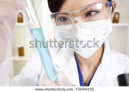 A Chinese Asian female medical or scientific researcher or doctor using looking at a test tube of blue liquid in a laboratory