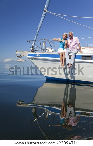 A happy senior couple sitting on the front of a sail boat on a calm blue sea