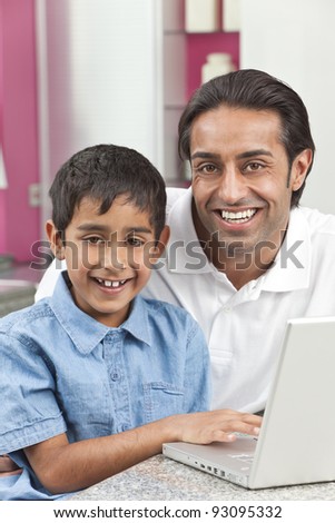 Asian Indian father and son, man and boy, using laptop computer in the kitchen at home