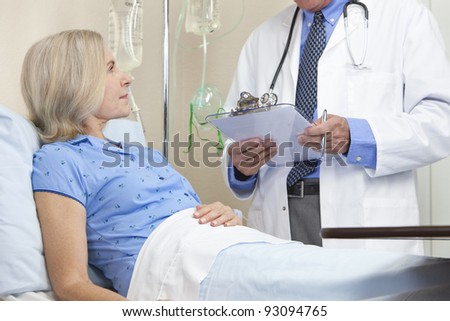 Senior woman in a hospital bed having talking to male doctor with stethoscope and clipboard