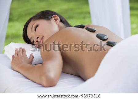 An Asian Chinese woman relaxing outside at a health spa while having a hot stone treatment or massage