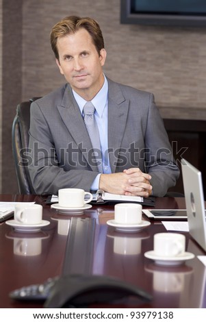 A businessman, chairman or man in a business suit, sitting at an office boardroom table