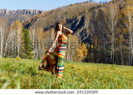 The happy young woman in the autumn wood of the mountain