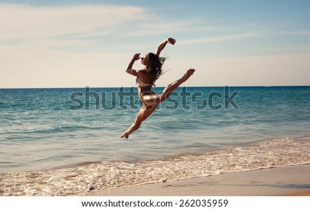 The girl is happy dances at sunset on the seashore