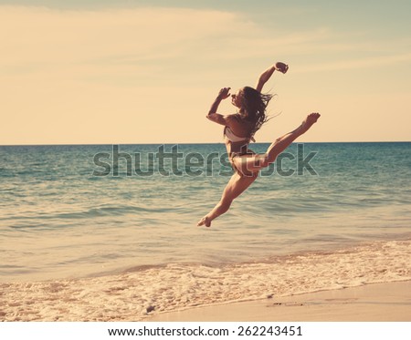 The girl is happy dances at sunset on the seashore