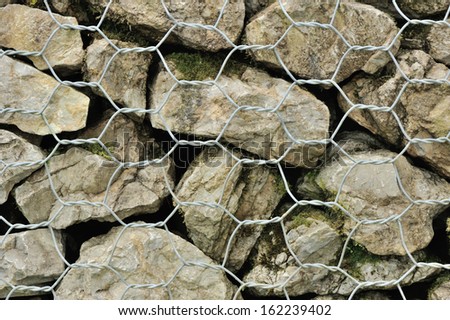 various stones carefully aranged in an iron net to make a wall
