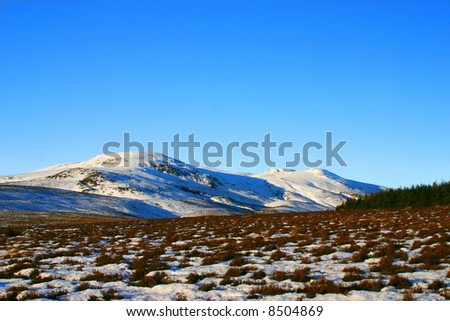 Scotland in winter with snow capped peaks below an ice blue sky