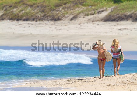 Beautiful surfer girls walking on the beach